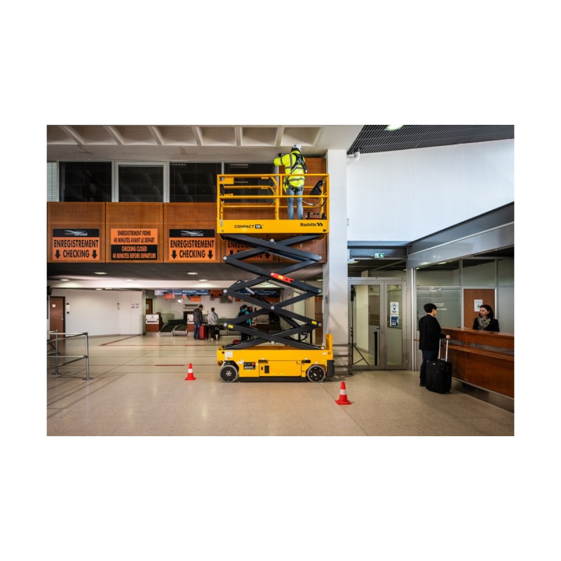 Person jobber med taket fra en Haulotte COMPACT 8 NAE sakselift inne på en flyplass