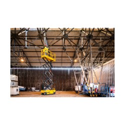 Haulotte COMPACT 10 NAE med hevet plattform i bruk av en arbeider innendørs